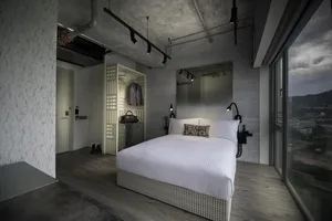 A modern industrial bedroom with concrete walls, flooring, and minimalist furniture.