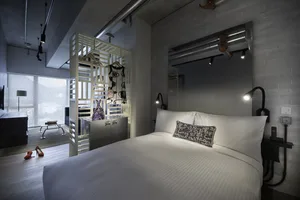 A modern industrial bedroom featuring a metal frame bed, concrete walls, and a minimalist design.