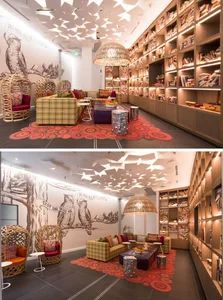 A modern library space with a ceiling adorned with paper shapes, wooden shelves filled with books, and a cozy seating area wi