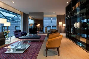 Modern living room with leather couches, glass tables, and wooden flooring.