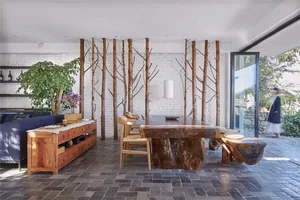 A modern living room featuring a wooden table and chairs with a white lamp and a green plant on a wooden table. The back wall