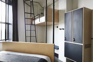 A minimalist bedroom featuring a modern design with wooden furniture and a metal ladder.