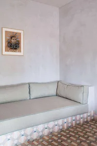 A minimalist sofa with fabric upholstery and a tiled floor.