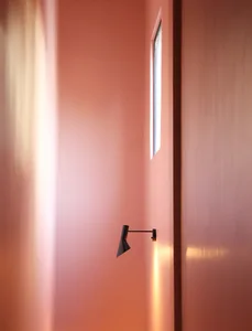 Modern minimalist interior with a wall lamp casting light on the wall.