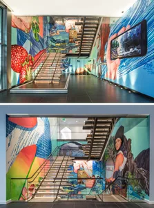 A modern staircase adorned with a large, colorful mural featuring various images and scenes.