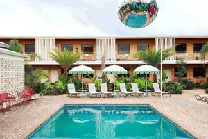 A modern vacation resort with a swimming pool, surrounded by umbrellas and chairs, featuring a concrete floor and brick walls