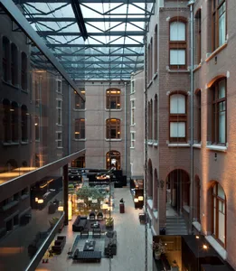 Indoor hotel lobby featuring exposed brick walls, glass walls, and modern furniture.