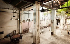 工業風餐廳室內，混凝土地板、鋼柱與玻璃吊燈。