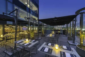戶外用餐區配有金屬家具、玻璃欄杆與混凝土地板，餐桌已擺設餐具與罐子