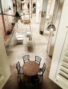 Industrial-style café interior featuring exposed concrete flooring, minimalist white furniture, and sparse lighting fixtures.