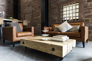 A cozy industrial living room with leather furniture, wooden coffee table, and brick walls