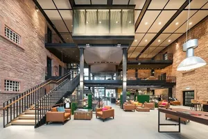 Industrial-style lobby featuring wooden furnishings and a mid-level balcony.