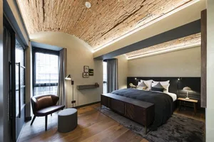 A bedroom with a rustic brick ceiling, wooden floors, and industrial-style decor.