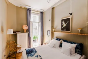 A minimalist bedroom with blue walls, swan artwork, and alternating hanging light bulbs.