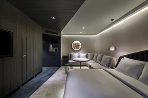 A modern minimalist hotel room featuring concrete flooring and steel accents.