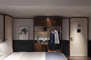 Modern bedroom featuring a bed with white bedding, a wooden wardrobe with clothes, and decorative objects.
