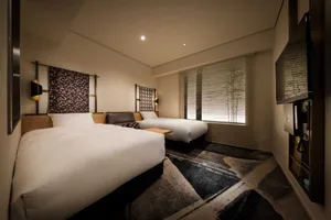 Modern bedroom featuring a cozy feel with textured fabric on the bed, white walls, and hardwood floors.