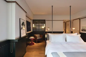 A modern bedroom featuring a wooden floor and concrete walls.