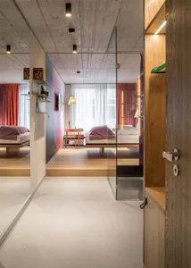 Modern hotel suite with wooden flooring and furniture, minimalistic design, and large windows.