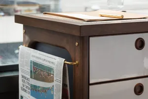 A modern office desk with a newspaper hanging off the side.