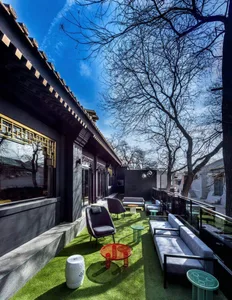 Outdoor balcony with synthetic grass, lounge furniture, and trees in the background