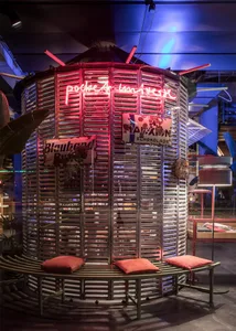 Industrial-style metal room with red neon lights and signage.