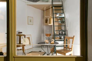 Industrial-style residential interior with wooden furniture, metal stairs, and ceramic items.