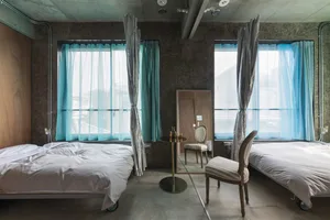 Minimalist bedroom with concrete walls and two twin beds.