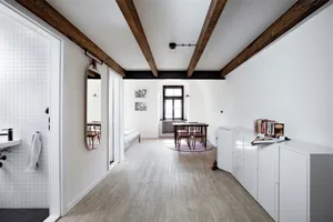 A minimalist living room with wooden elements and a dining area.