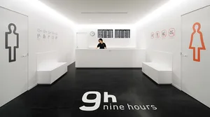 A minimalist white office reception area with black flooring and detailed signage.