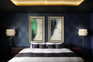 A modern bedroom featuring a bed with fabric and wooden headboard, surrounded by black circular-patterned wallpaper, and flan