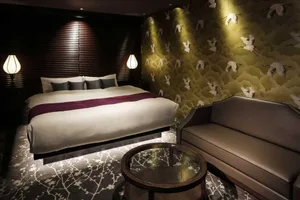A modern, clean bedroom with a bed, sofa, and table lamp.