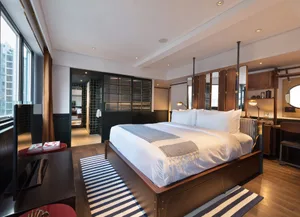 A modern bedroom with a wooden bed frame, white bedding, and striped rug.