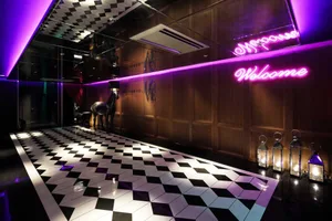 A stylish, modern hotel lobby featuring a black and white checkered floor with metallic elements and decorative lanterns.