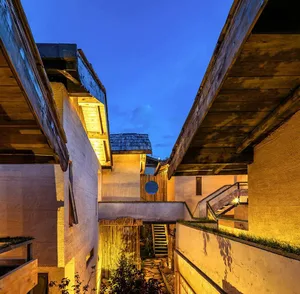 A modern house with wooden and concrete exterior, featuring a narrow alleyway at dusk with warm lighting.