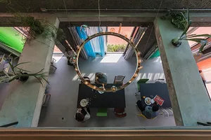 Modern industrial living room featuring concrete flooring, hanging circular light fixture, and indoor plants.