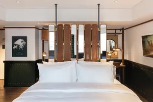 A minimalist bedroom with a large bed, white bedding, and a wooden headboard.