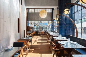 Modern restaurant interior with wooden tables and blue tiled walls