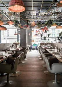 Modern restaurant interior with wooden flooring, colorful pendant lights, and contemporary seating.