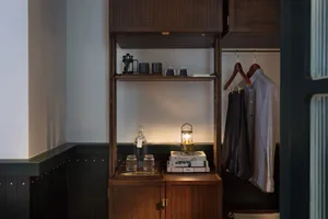 A modern wardrobe with dark wood shelves and clothing hanging inside.