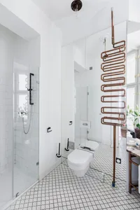 Modern bathroom featuring white tiles and copper pipes