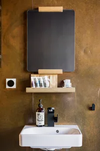 White sink with black faucet and concrete shelf with toiletries.