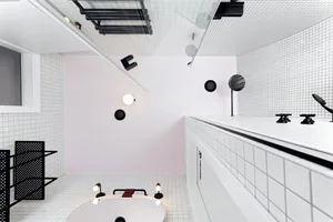 A modern bathroom with white tiled walls, black accents, and minimalist design.