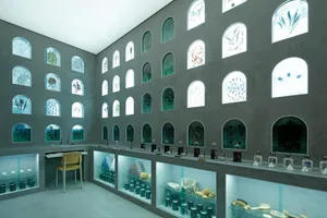 Industrial storefront with large glass windows, showcasing a collection of objects.