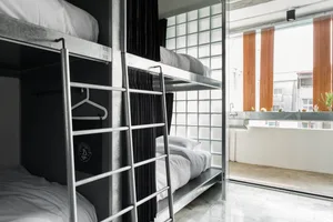 Metallic bunk beds with white bedding in an industrial-style hostel bedroom