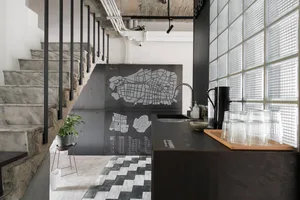 Industrial kitchen with concrete stairs, glass block wall, and concrete counter with black map.