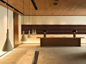 An industrial-style office space with concrete flooring, minimalist furniture, and exposed wooden ceiling beams.