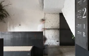 A minimalist cafe interior featuring concrete walls and furniture.