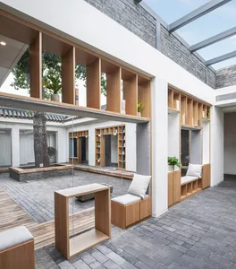 A minimalist courtyard library featuring wooden shelves, concrete pavers, and plants.