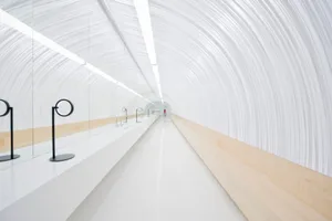 A minimalist white corridor with wooden accents and linear lighting.